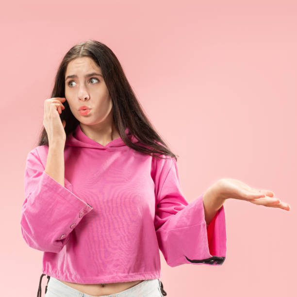 istock Young beautiful woman using mobile phone studio on pink color background 1061346052