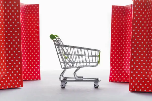 Shopping cart empty and red bags on a white background. Store ad concept. Copy space