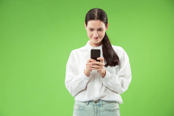 istock Young beautiful woman using mobile phone studio on green color background 1061354340