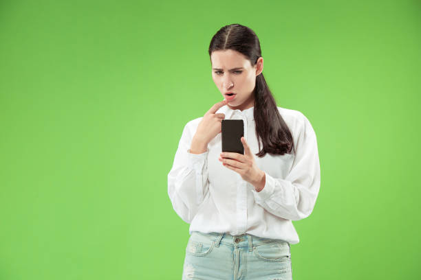 istock Young beautiful woman using mobile phone studio on green color background 1061354366