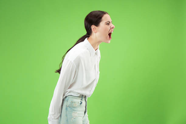 istock Isolated on green young casual woman shouting at studio 1061354628