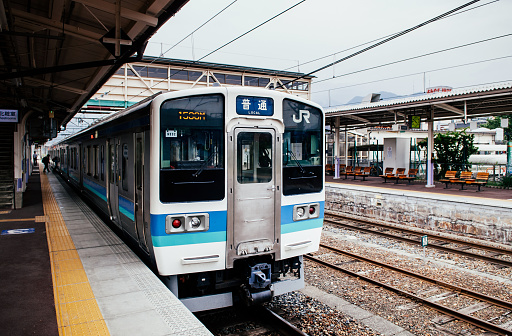 MAY 28, 2013 Shinano Omachi, Nagano, Japan - Local JR train line stop at platform of Shinano Omachi station with Japanese passengers on platform