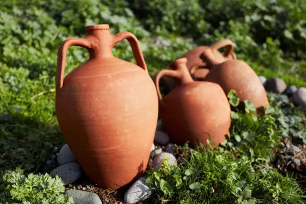 Vintage earthenware clay pots for wine and water containment used as decorative objects in a garden