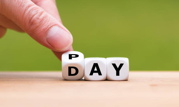 Hand is turning a dice and changes the word Pay to Day stock photo