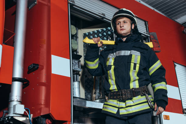 istock low angle view of firefighter in helmet with axe looking away at fire station 1061369982