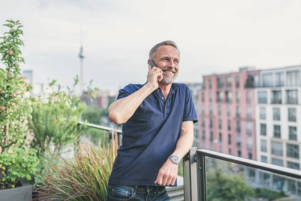 istock bearded midaged man talking on mobile at balcony in Berlin 1061373820