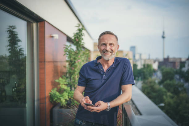 istock bearded midaged man tapping on mobile at balcony in Berlin 1061373870