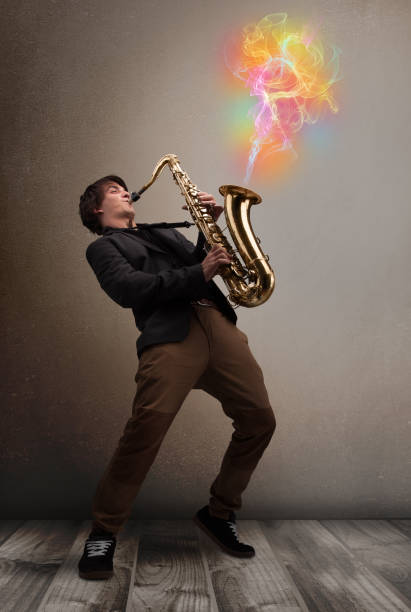 привлекательный музыкант, играющий на саксофоне с красочным абстрактным дымом выходит - comming стоковые фото и изображения