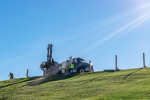 Halifax, Canada - October 20 2016: Caucasian male Engineers working and operating a hydraulic telescopic truck mounted auger crane drill rig on a hill on a sunny day.