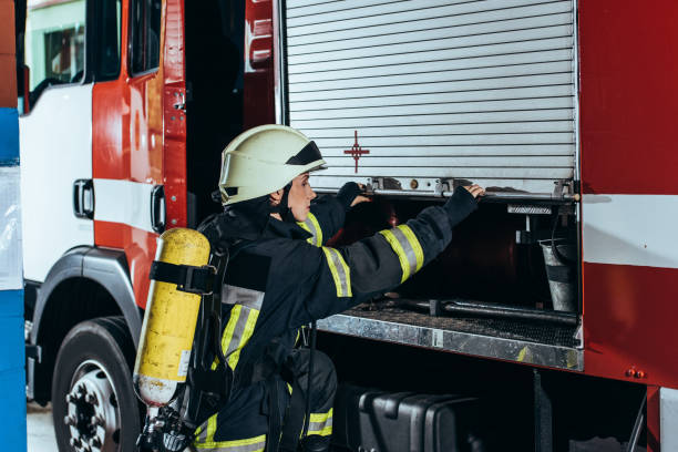 istock female firefighter with fire extinguisher on back closing truck at fire station 1061386140