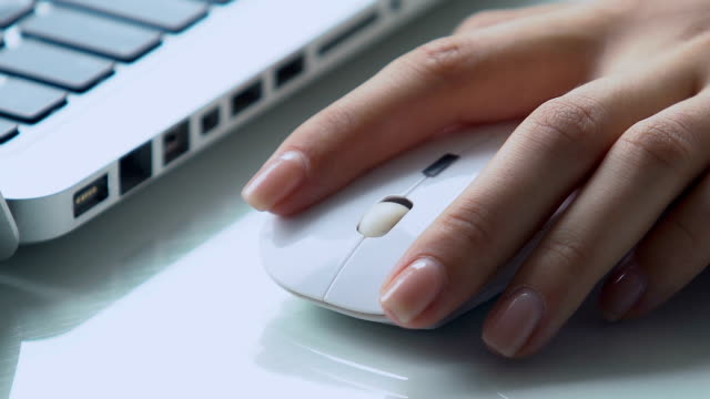 Female hand using wireless computer mouse on office desk, business innovations