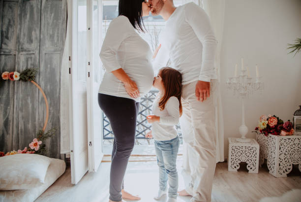 Pregnant mother and son whispering at home