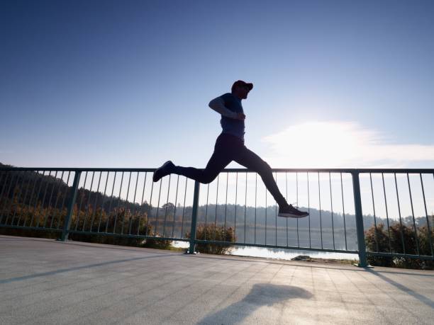 istock Side view silhouette of runner man running on beach bridge 1061389930