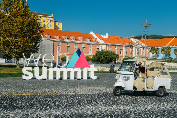 Lisbon, Portugal - Oct 24, 2018: Tuk Tuk next to a sign advertising the World Web Summit, the largest technology convention in the world and Europe to be held in Lisbon in November