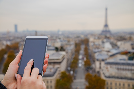 Using cellphone with Eiffel tower, Paris in the background.