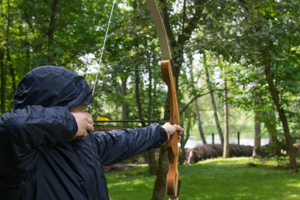 istock a man in a hood, pulls a bow string and takes aim at a shot at the target 1061401974