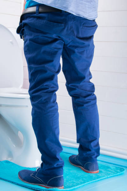 istock man in blue pants peeing in toilet, rear view 1061407478