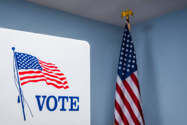 istock Looking up at empty voting booths with American flag at polling station 1061419330