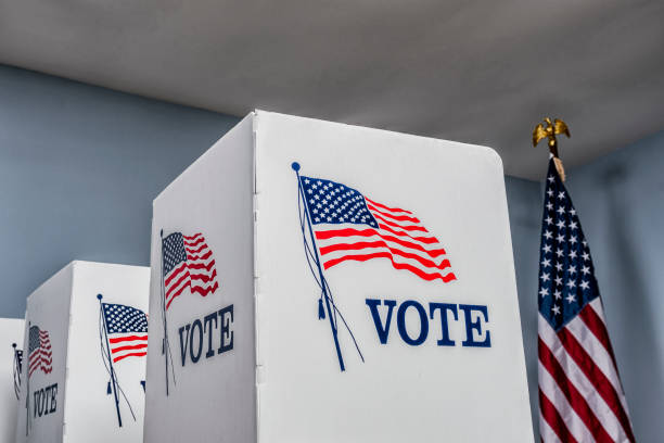 istock Looking up at empty voting booths with American flag at polling station 1061419350