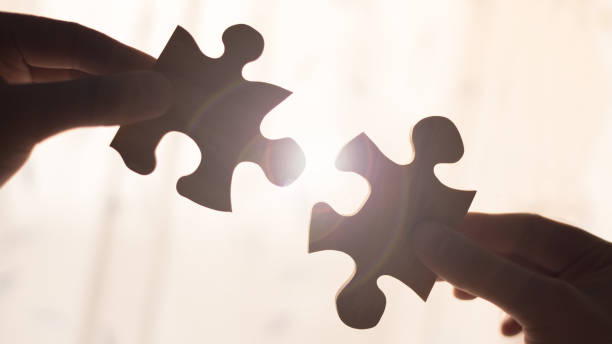 Two hands trying to connect couple wooden puzzle piece. Concept of association and connection, business strategy. stock photo