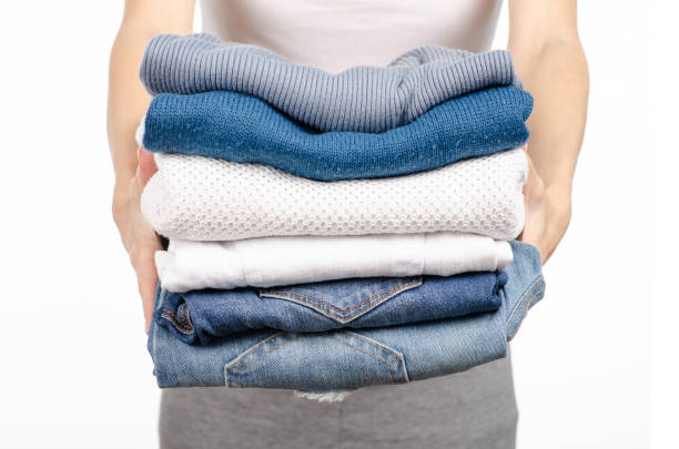 istock A stack of sweaters jeans in the hands of a woman 1061436806