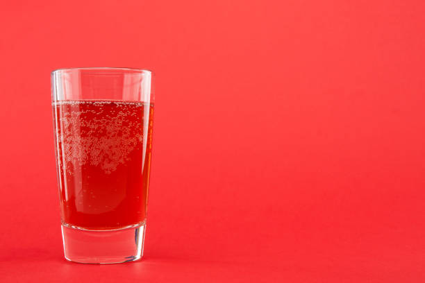 líquido vermelho (água) em um copo sobre um fundo escarlate com espaço de cópia - food and drink concepts and ideas macro studio shot - fotografias e filmes do acervo