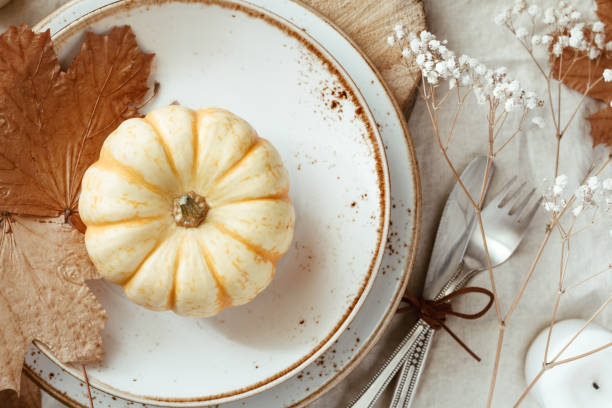 istock Top view on a decorated table setting for Thanksgiving dinner. Autumn ornate, white pumpkin on ceramic plates. 1061439118
