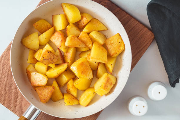 istock Top view on roasted potato in a white pan on a kitchen table. Modern style, vegetarian food. 1061439154