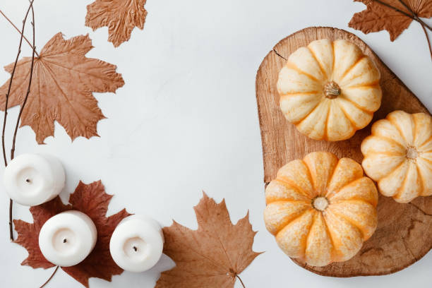 istock Top view on Autumn flat lay with dead maple leaves, white candles and three small pumpkins on a wooden tray. Flat lay, copy space. 1061439182