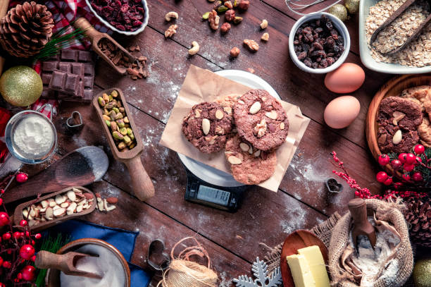 biscotti al cioccolato e noci sulla bilancia digitale del peso alimentare della cucina.  temi natalizi. - biscotti cookie chocolate pistachio foto e immagini stock