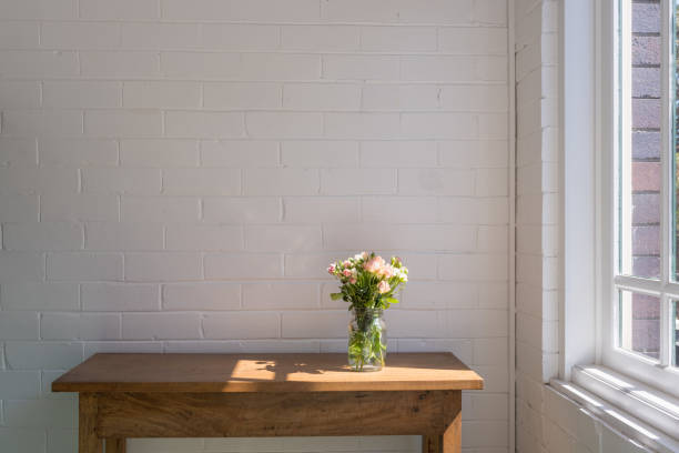 istock Small pink roses on wooden table next to window 1061447414