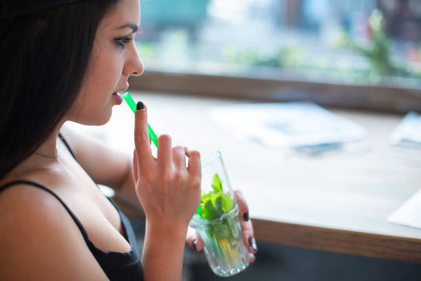 istock A young girl drinks a mojito through a straw while sitting in a cafe by the window. 1061450700