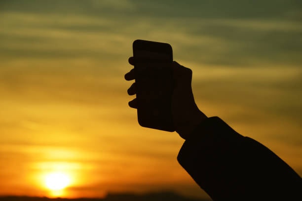 istock Male hand holding smart phone at the sunset 1061458794