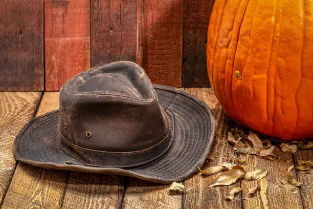 weathered outback hat and pumpkin against rustic red barn wood