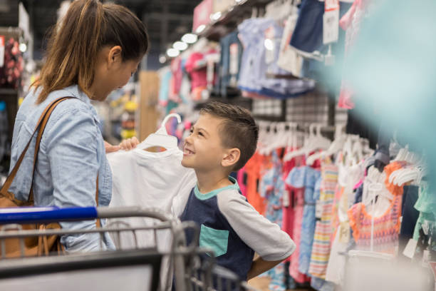 A mother and son search for new clothes together in the supermarket. They look at each other and smile.