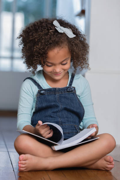 istock Curly haired preschool age girl smiles while reading a book 1061484546
