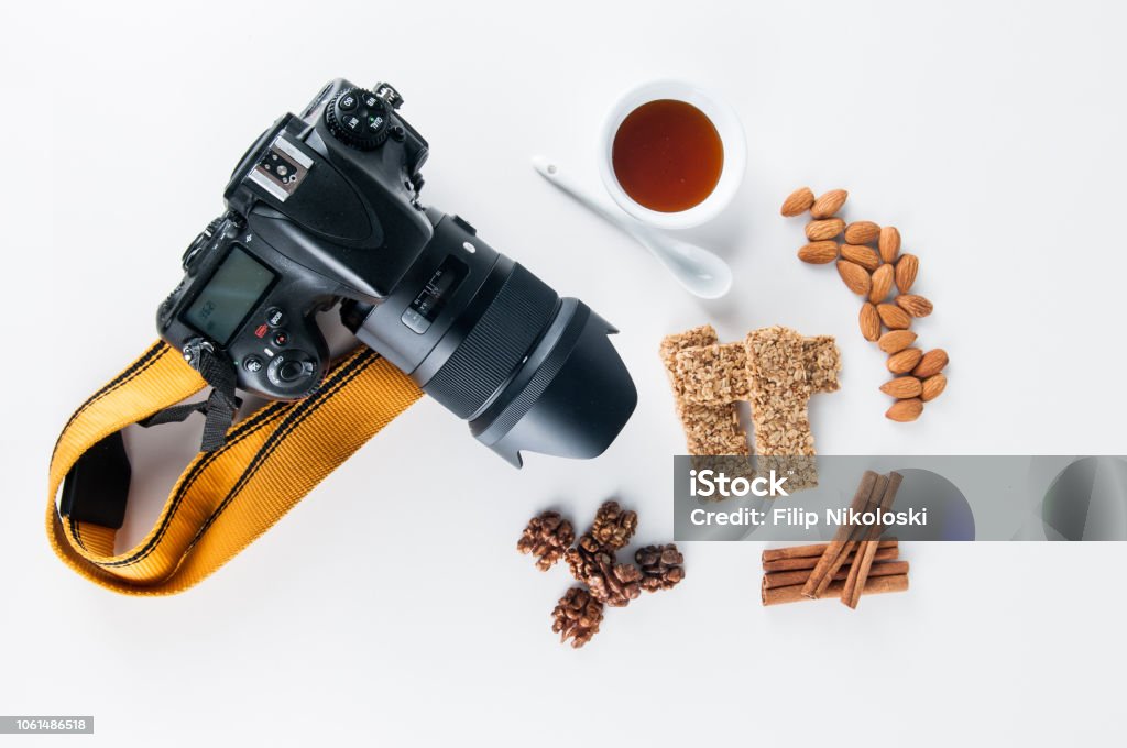 Healthy food + Nikon Cereals with honey, nuts, cinnamon rolls, almond & dslr camera on white background Almond Stock Photo