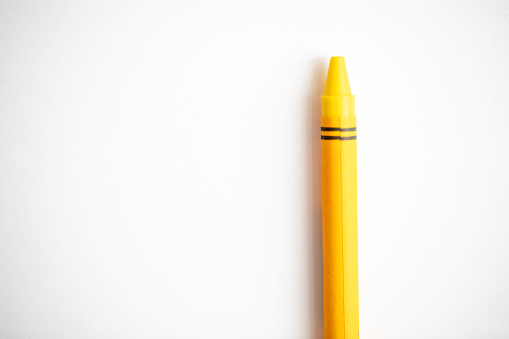 Yellow crayon shot up close on a white background