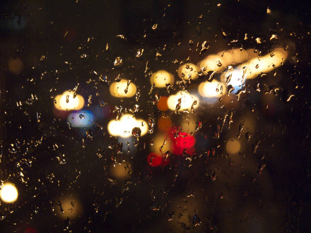 istock Raindrops on wet blurred window glass and traffic lights in the night 1061495480