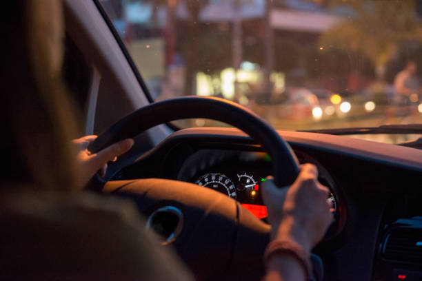 mujer conduce coche holding suburbanos de gas bajo volante - car driving dashboard night fotografías e imágenes de stock