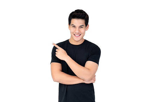 Isolated portrait of  happy smiling Asian man wearing casual black t-shirt pointing hand to empty space aside studio shot white background