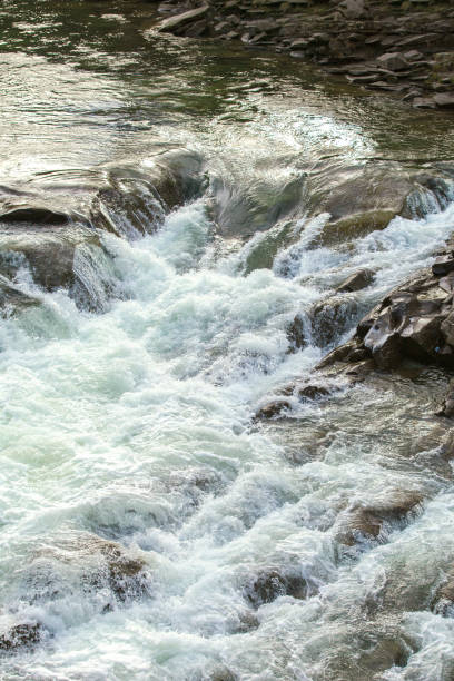 istock Clear river with rocks leads towards mountains, small waterfall 1061510890