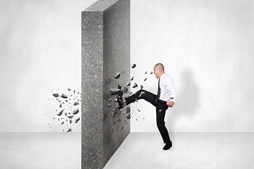 Businessman breaking wall of obstacle by kick. Business challenge conquering adversity concept