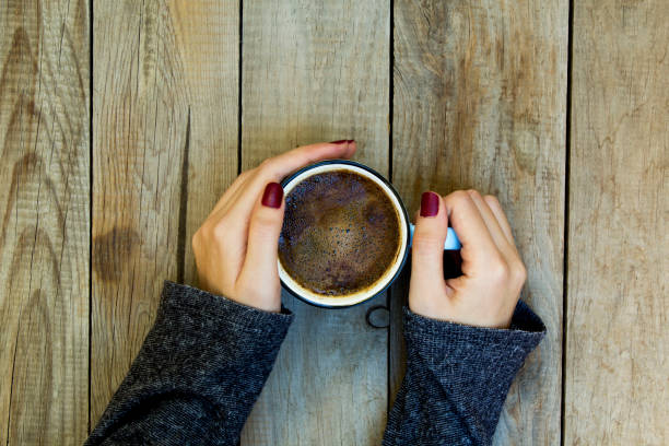 istock Woman hand holding coffee cup on wooden table. 1061530234
