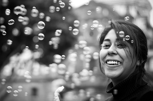 Beautiful young Mexican woman smiling and playing with bubbles in a plaza in Puebla