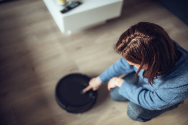 istock Lady turning on robot vacuum cleaner 1061543586