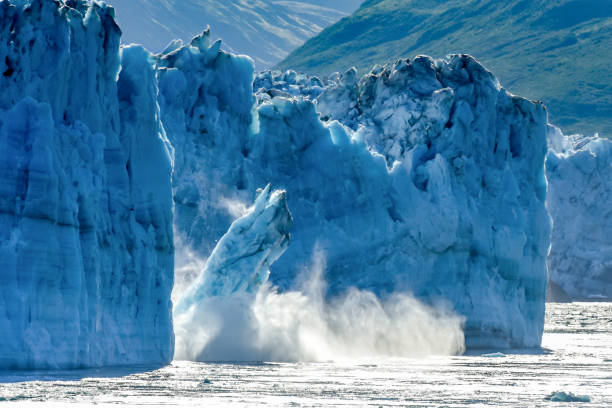 Calving Glacier Alaska - Hubbard Glacier - a huge iceberg calves into Disenchantment Bay - St. Elias Alaska. Taken from an Alaska cruise ship - near Yukon, Canada One of the most popular stops on an Alaskan cruise / Alaska vacation, Hubbard Glacier is a very active calving glacier. Unlike most glaciers, Hubbard is advancing vs. receding. Despite it's advancing status, this photo is often used to depict global warming and climate change as a massive piece of Hubbard glacier calves off into Disenchantment Bay polar climate stock pictures, royalty-free photos & images