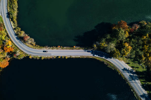 istock Road in the autumn forest aerial view with lake 1061550046