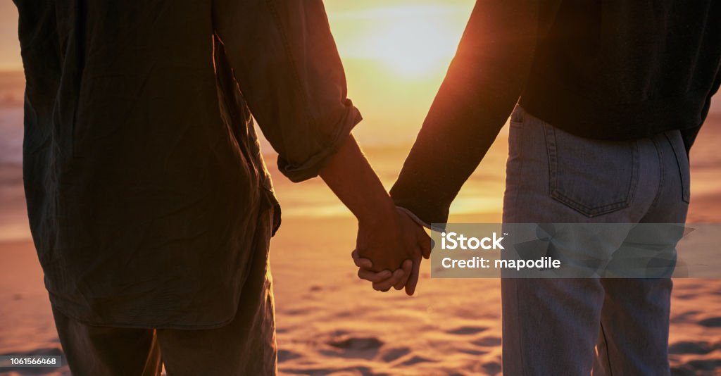 Take my hand and never let go Cropped shot of a young couple holding hands on the beach at sunset Adult Stock Photo