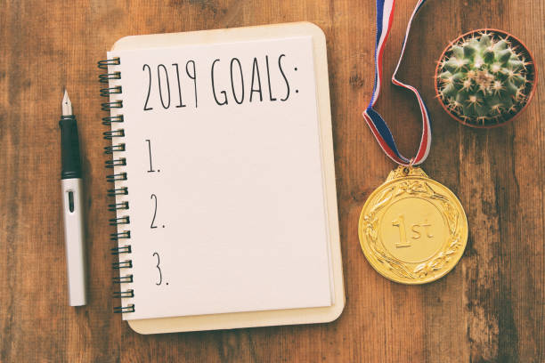 istock Top view 2019 goals list with notebook over wooden desk. 1061568340